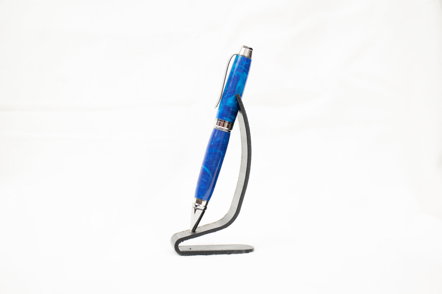 A handmade swirled blue cigar pen with chrome plating on a black stand