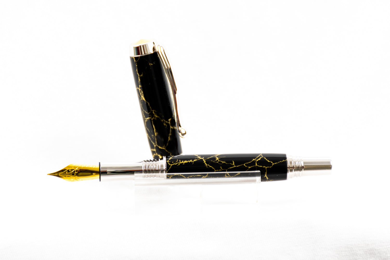 a handmade black and gold trustone fountain pen with rhodium plating on a clear stand