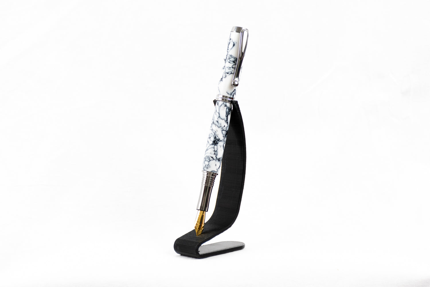 A handmade white and black marbled trustone fountain pen on a black stand