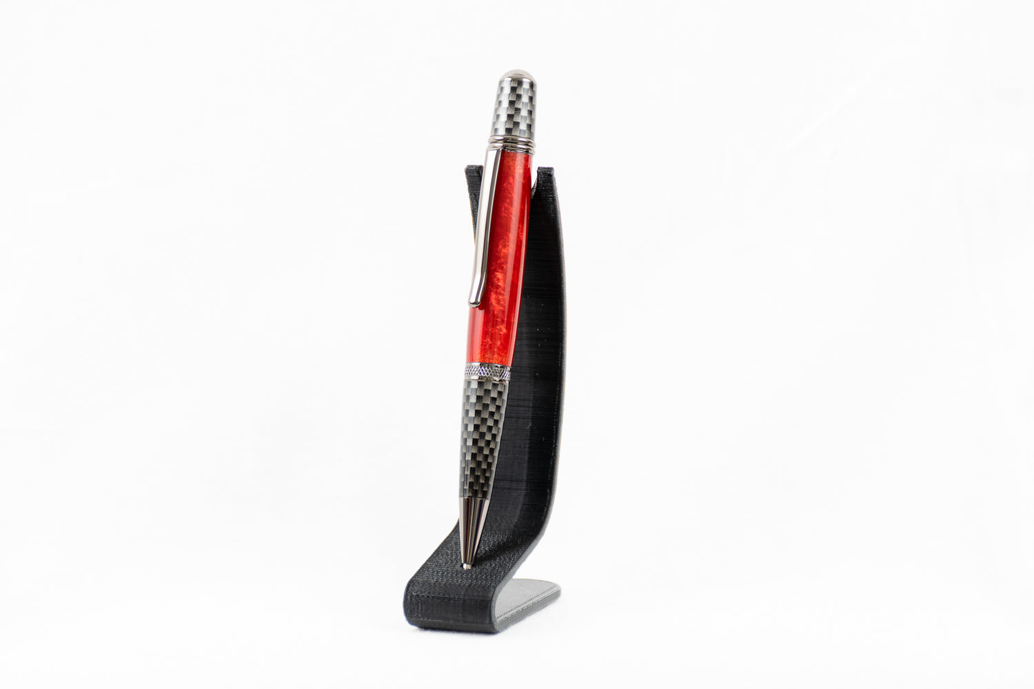 a handmade red resin pen with carbon fiber and chrome plating on a clear stand