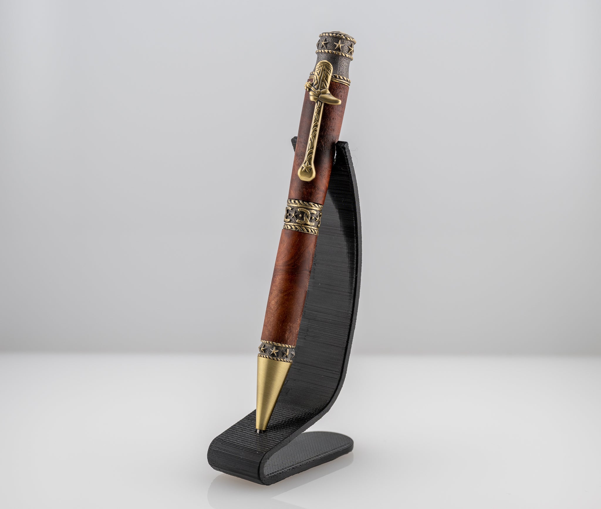 a handmade australian malle burl twist pen with cowboy features on a black stand
