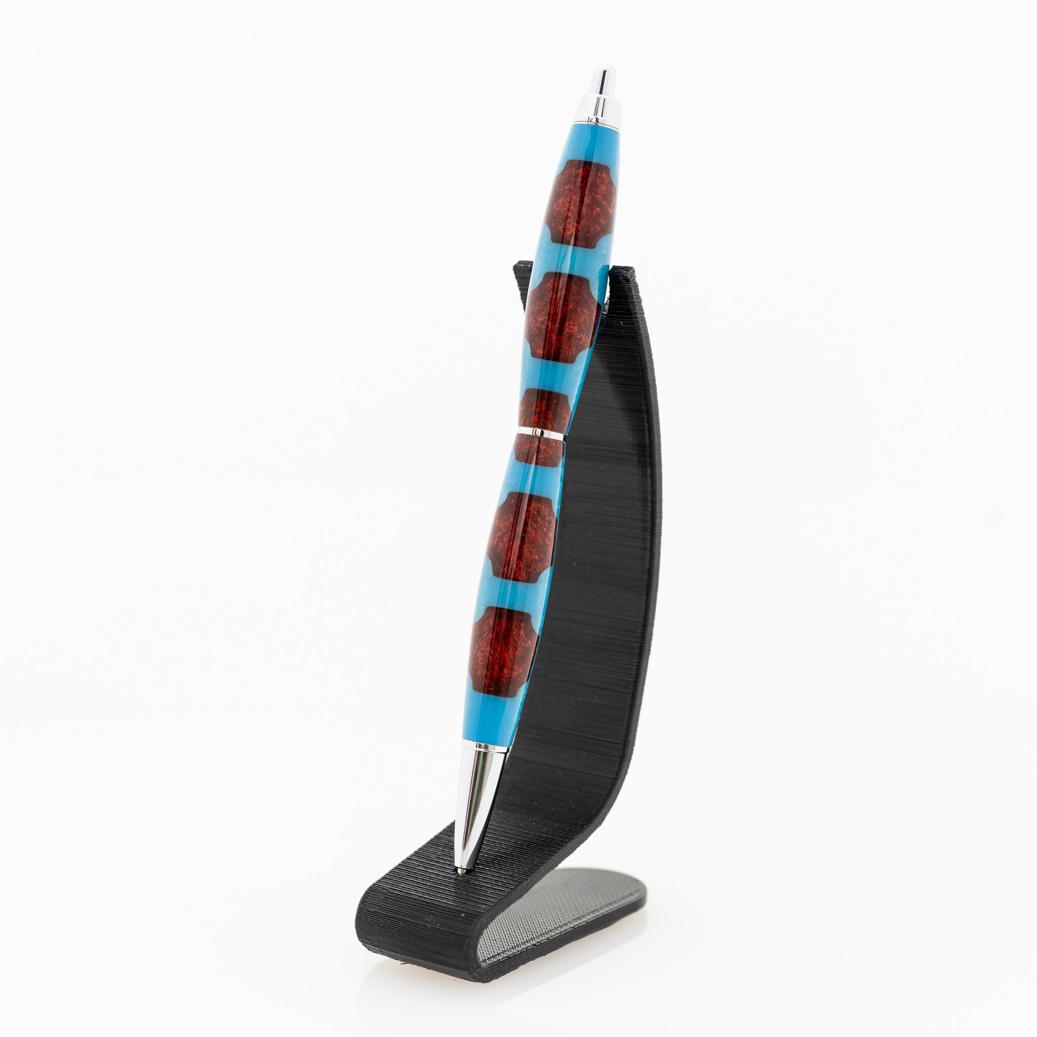 a handmade blue and red resin click pen on a black stand
