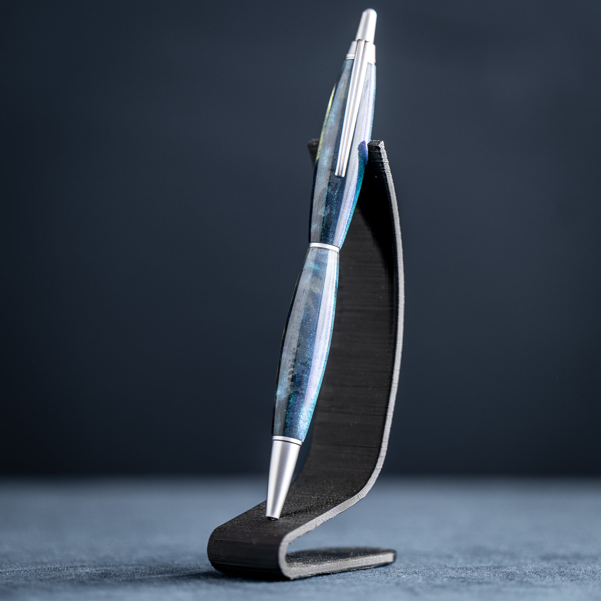 Blue and silver pen on a black stand against a dark background