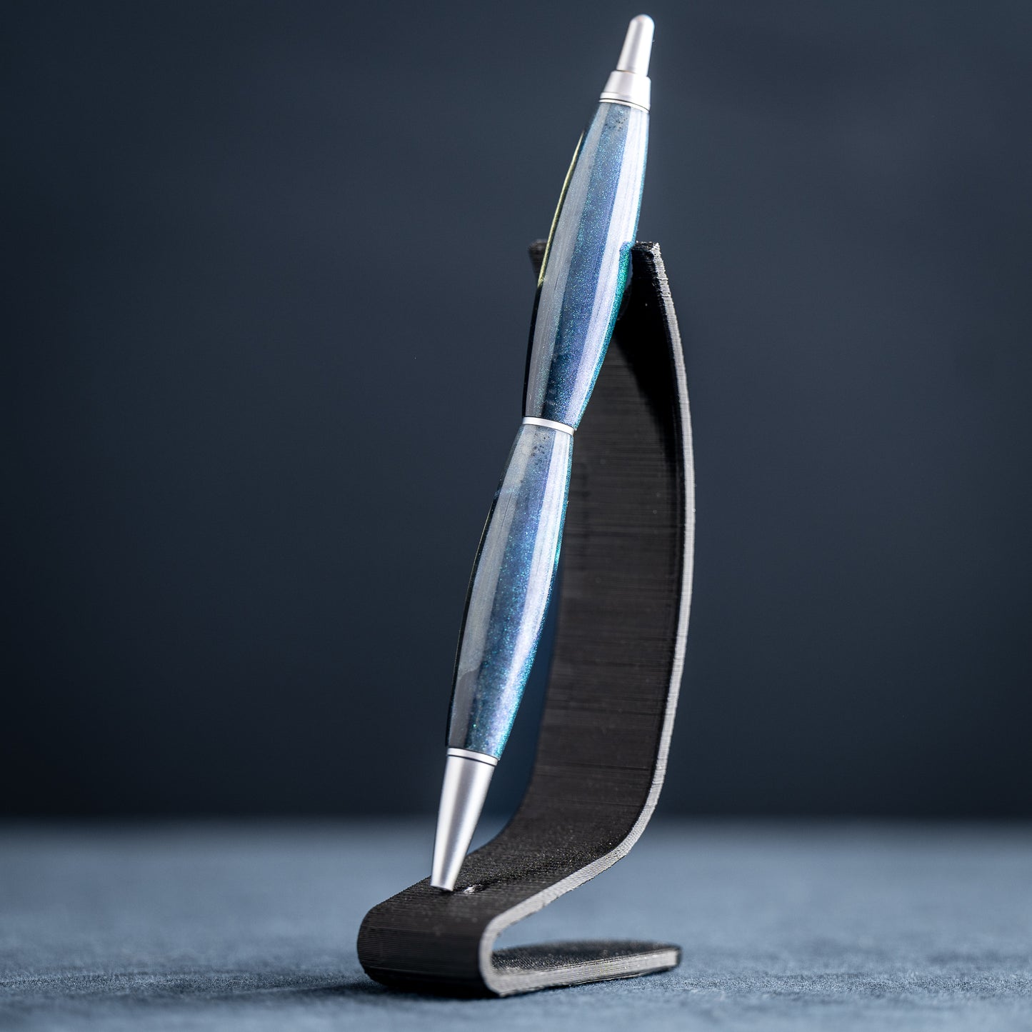 Silver pen on a black stand against a dark background