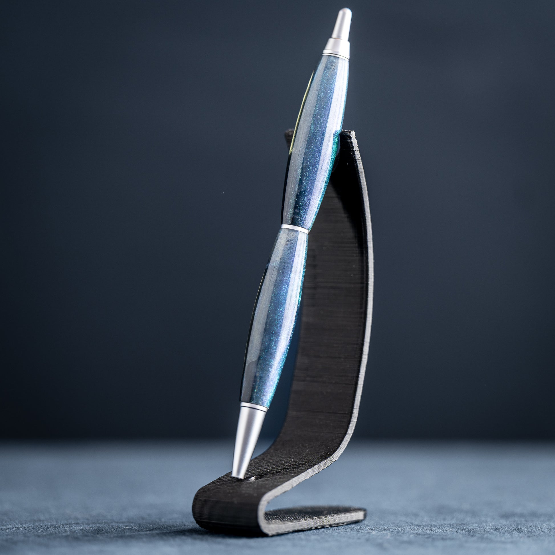 Silver pen on a black stand against a dark background