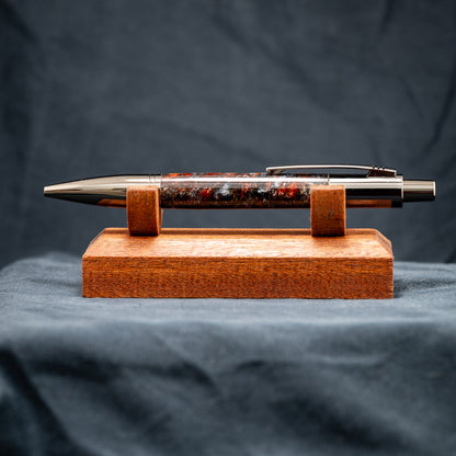 A handmade resin ballpoint click pen with bronze, copper, silver, and black metallic flakes and gunmetal plating.