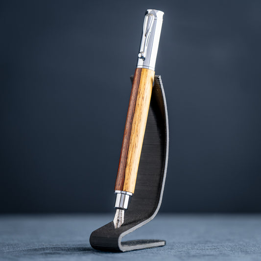 Handmade Cocobolo wood fountain pen with chrome plating on a black stand against a dark background