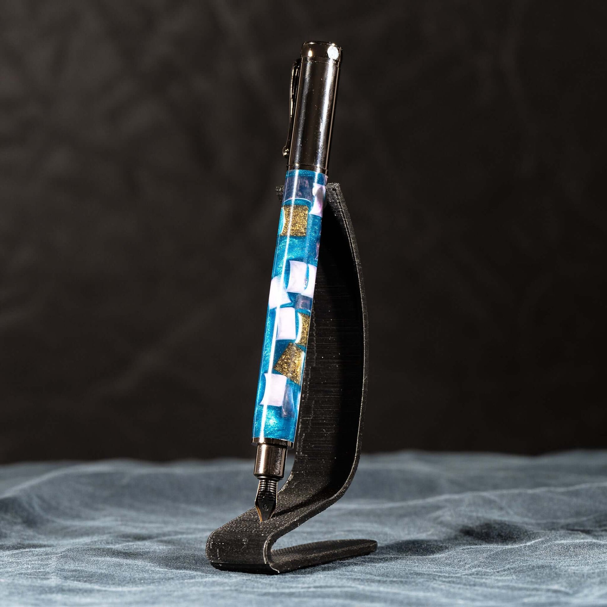 A handmade blue, white, and gold resin fountain pen with gun metal plating and a magnetic cap.