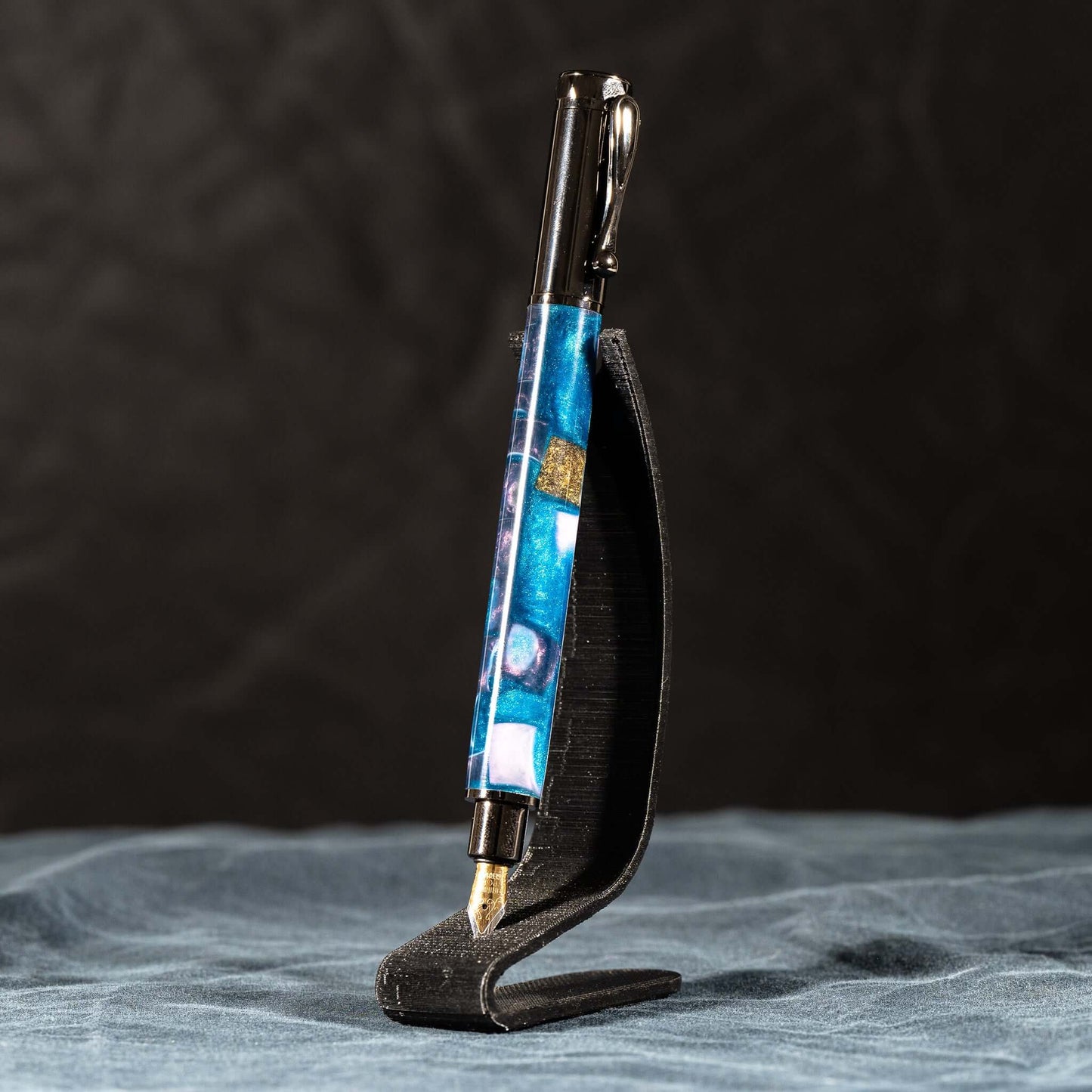 A handmade blue, white, and gold resin fountain pen with gun metal plating and a magnetic cap.