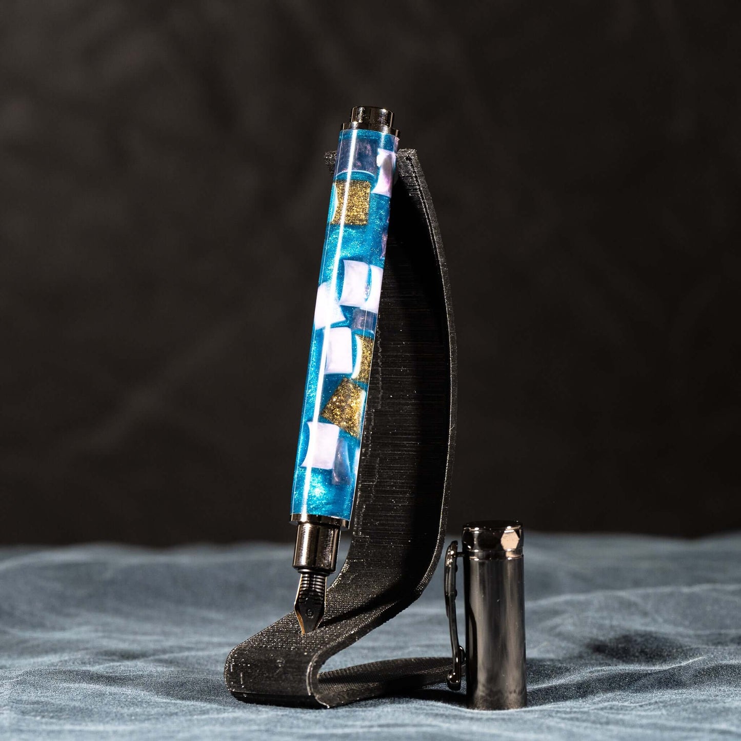 A handmade blue, white, and gold resin fountain pen with gun metal plating and a magnetic cap.