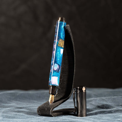 A handmade blue, white, and gold resin fountain pen with gun metal plating and a magnetic cap.