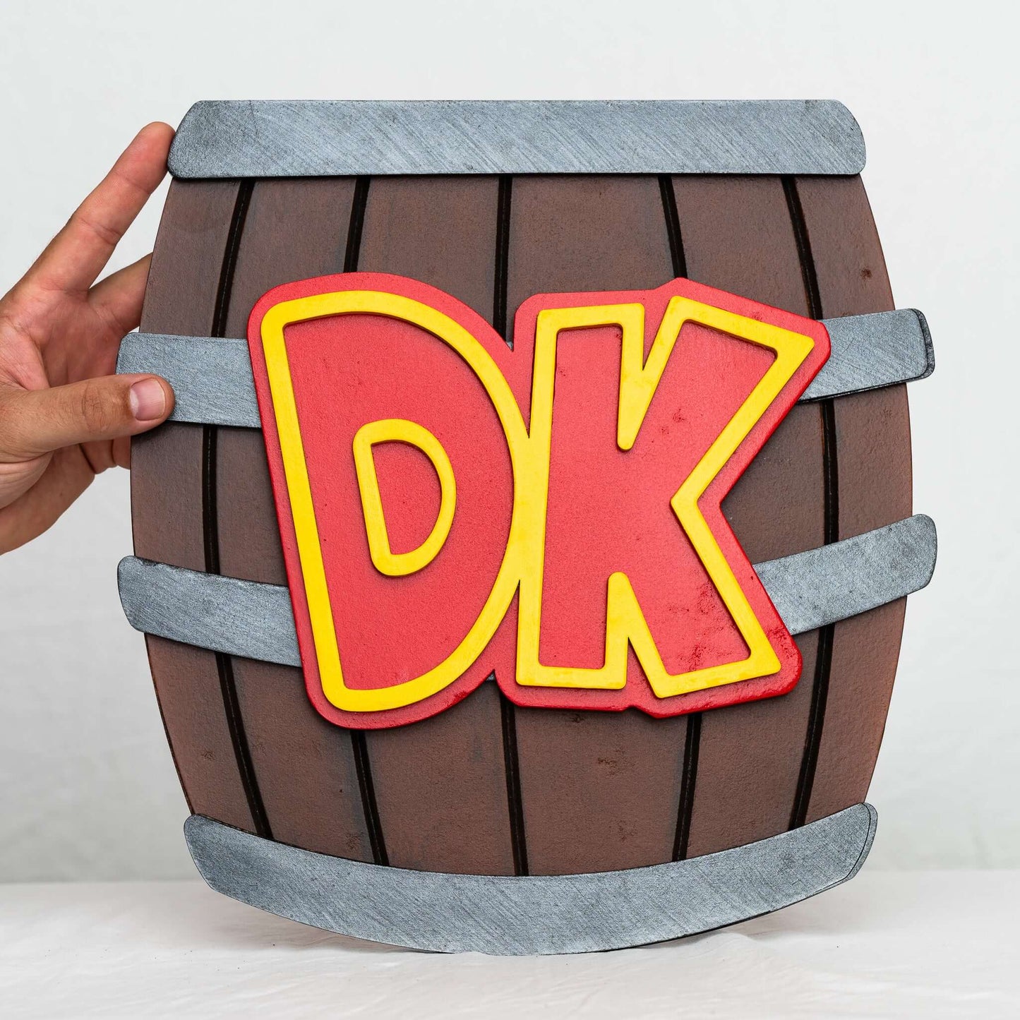 A handmade and hand-painted carved wooden sign featuring the barrel from the Donkey Kong series of Nintendo video games.