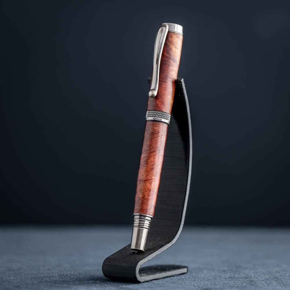 Handcrafted Australian Mallee Burl wood rollerball pen on a dark stand against a dark background.
