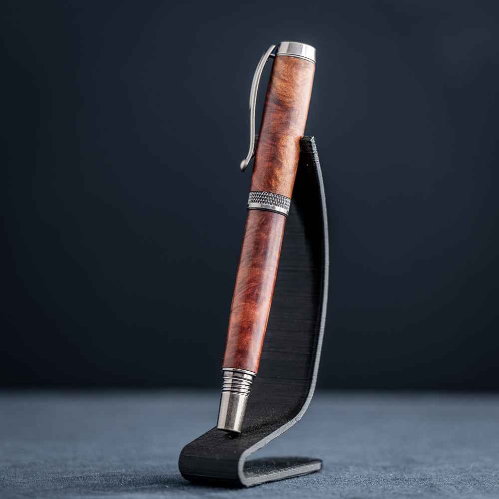 Handcrafted Australian Mallee Burl wood rollerball pen on a dark stand against a dark background.
