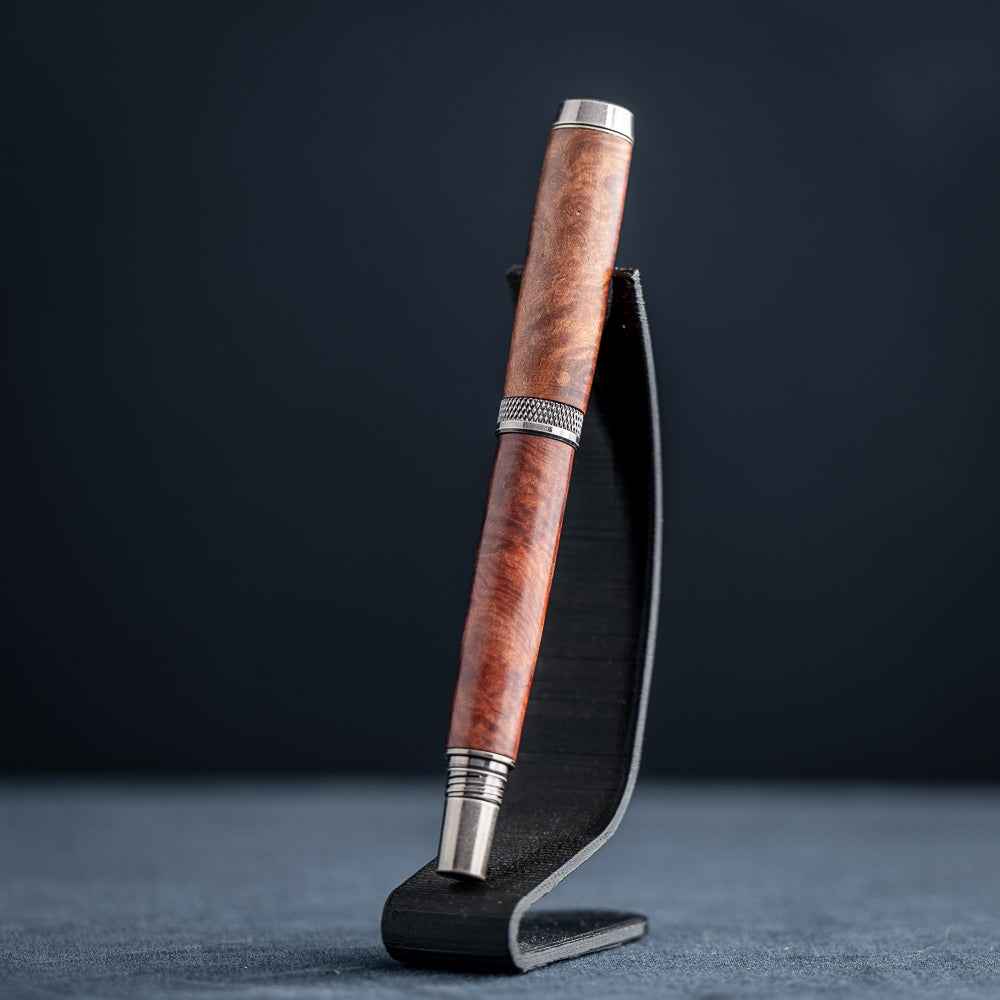 Handcrafted Australian Mallee Burl wood rollerball pen on a dark stand against a dark background.