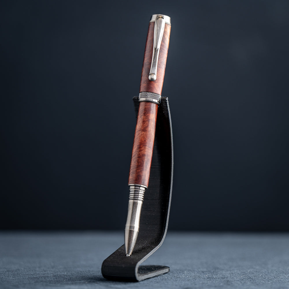Handcrafted Australian Mallee Burl wood rollerball pen on a dark stand against a dark background.