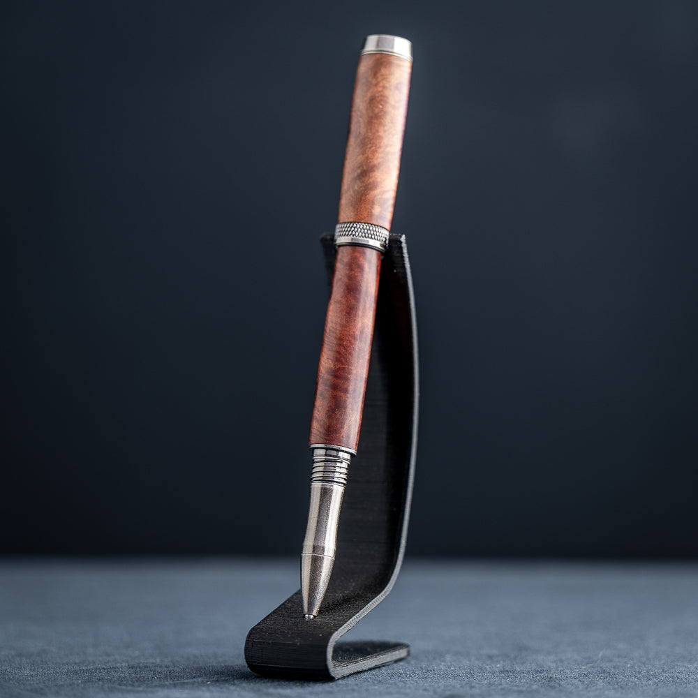 Handcrafted Australian Mallee Burl wood rollerball pen on a dark stand against a dark background.