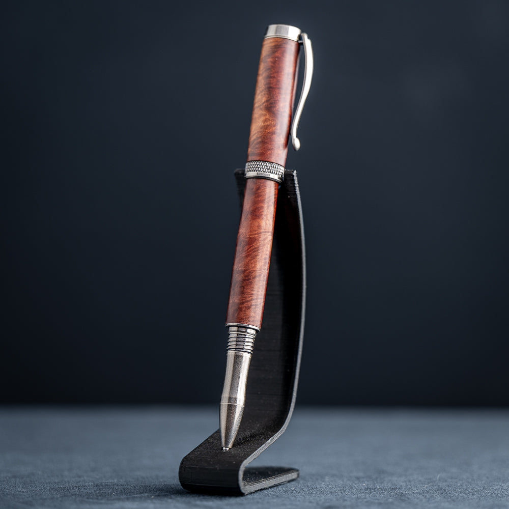 Handcrafted Australian Mallee Burl wood rollerball pen on a dark stand against a dark background.