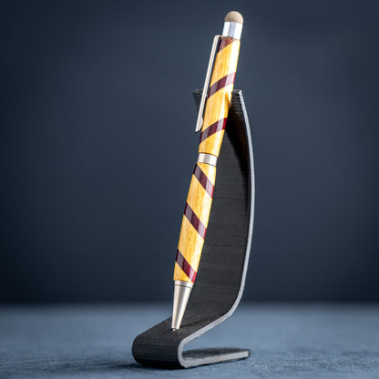 Handmade purple heart and canary wood ballpoint twist pen with stylus on a dark stand against a dark background.