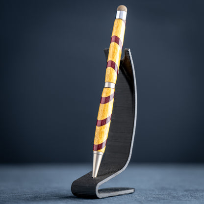 Handmade purple heart and canary wood ballpoint twist pen with stylus on a dark stand against a dark background.