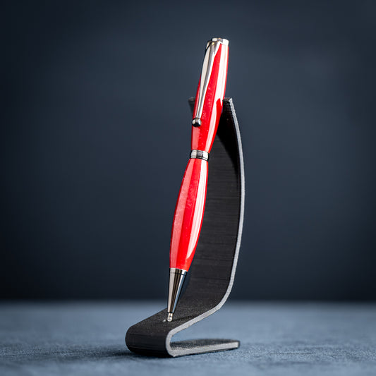 Handmade red and silver ballpoint pen on a black stand against a dark background