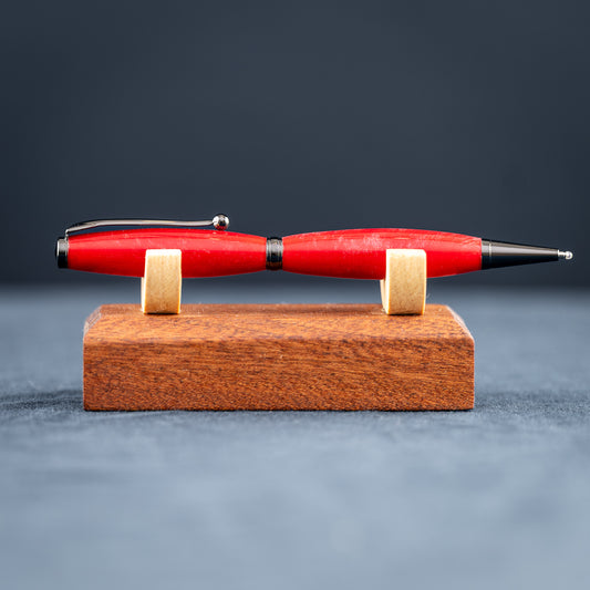 Handmade red and silver ballpoint pen on a wood stand against a dark background
