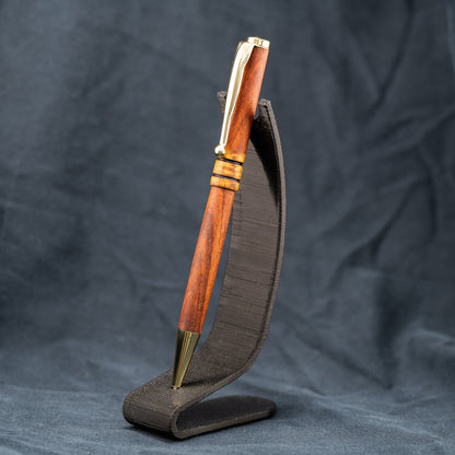 A handmade wooden twist pen made of Bolivian Rosewood and Curly Narra wood. The pen has black ink and gold plating.