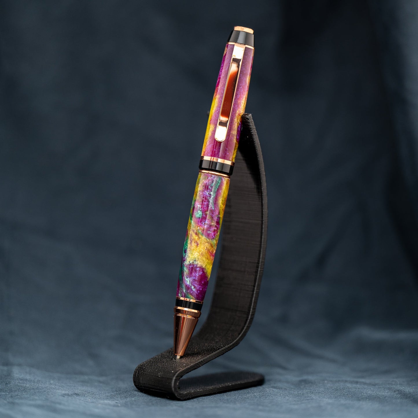 Handmade purple, green, and yellow resin twist ballpoint pen with bright copper plating and black ink.