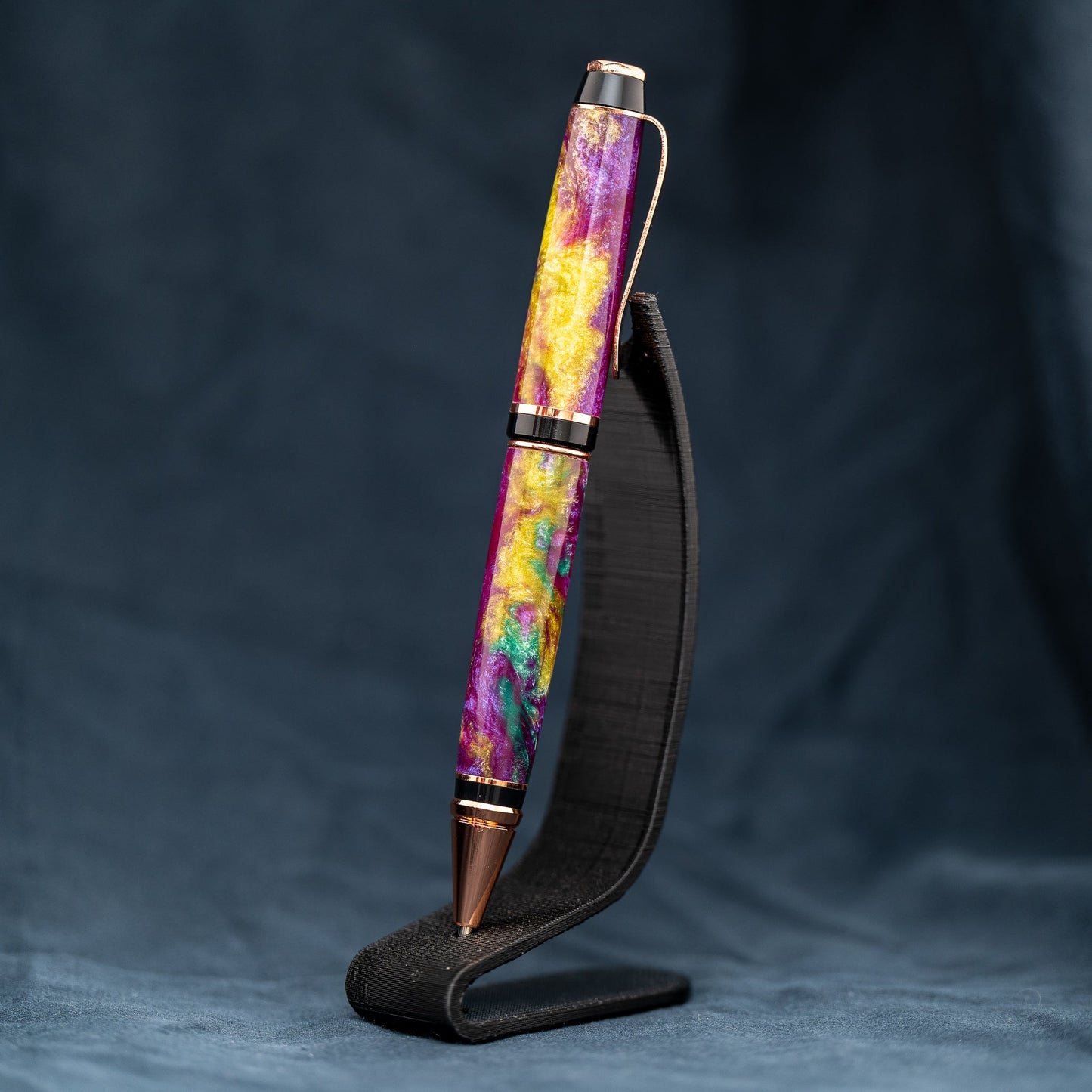 Handmade purple, green, and yellow resin twist ballpoint pen with bright copper plating and black ink.