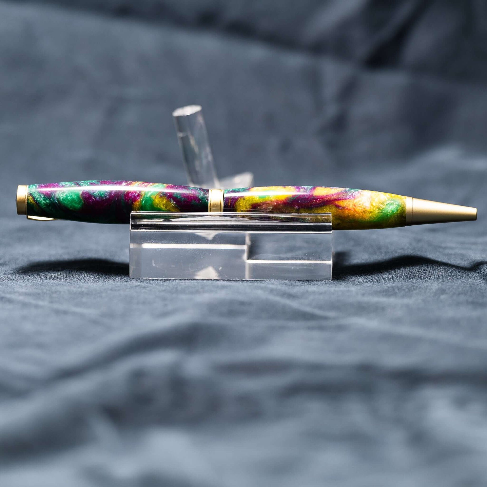 A handmade green, yellow, and purple resin ballpoint slimline twist pen with satin gold plating.