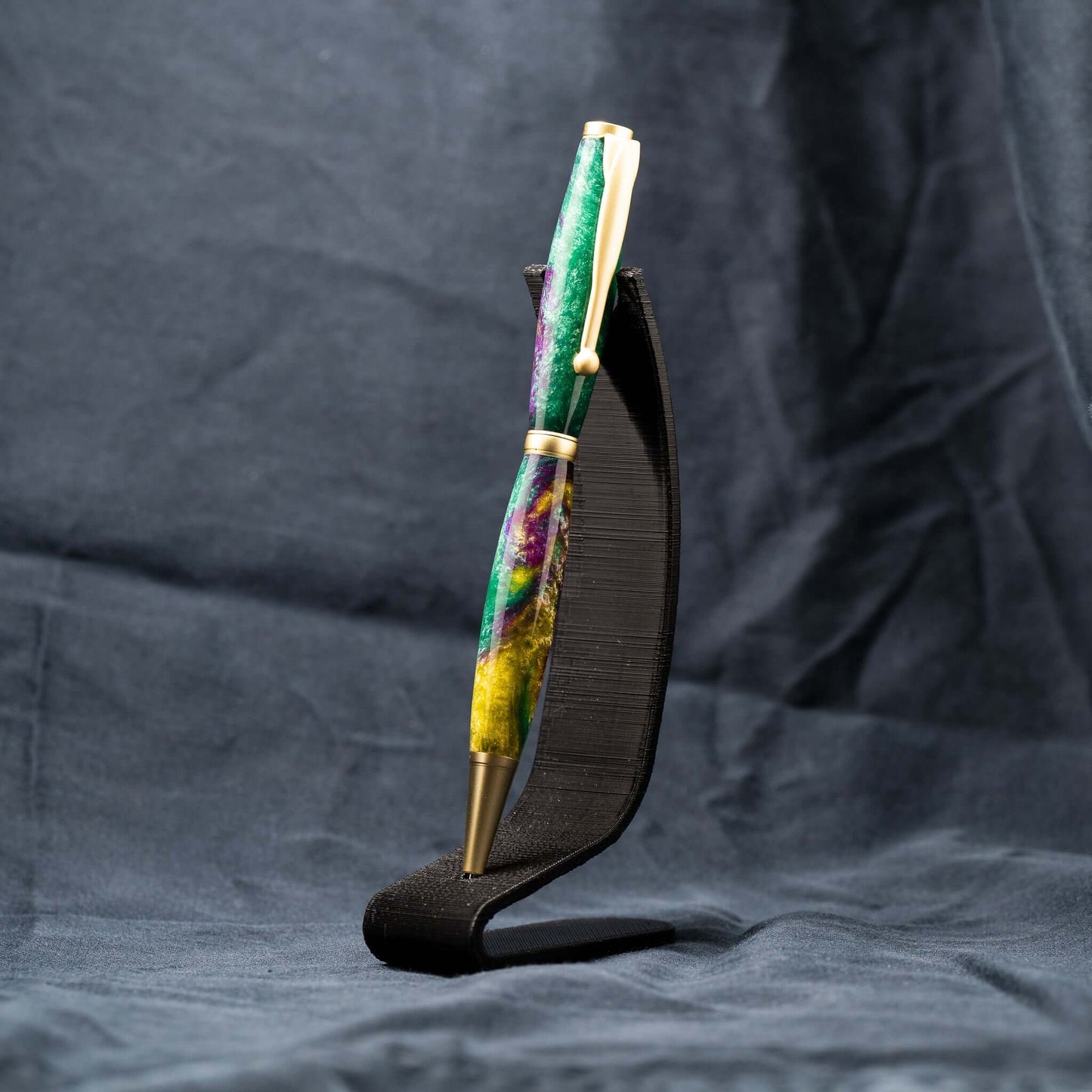 A handmade green, yellow, and purple resin ballpoint slimline twist pen with satin gold plating.