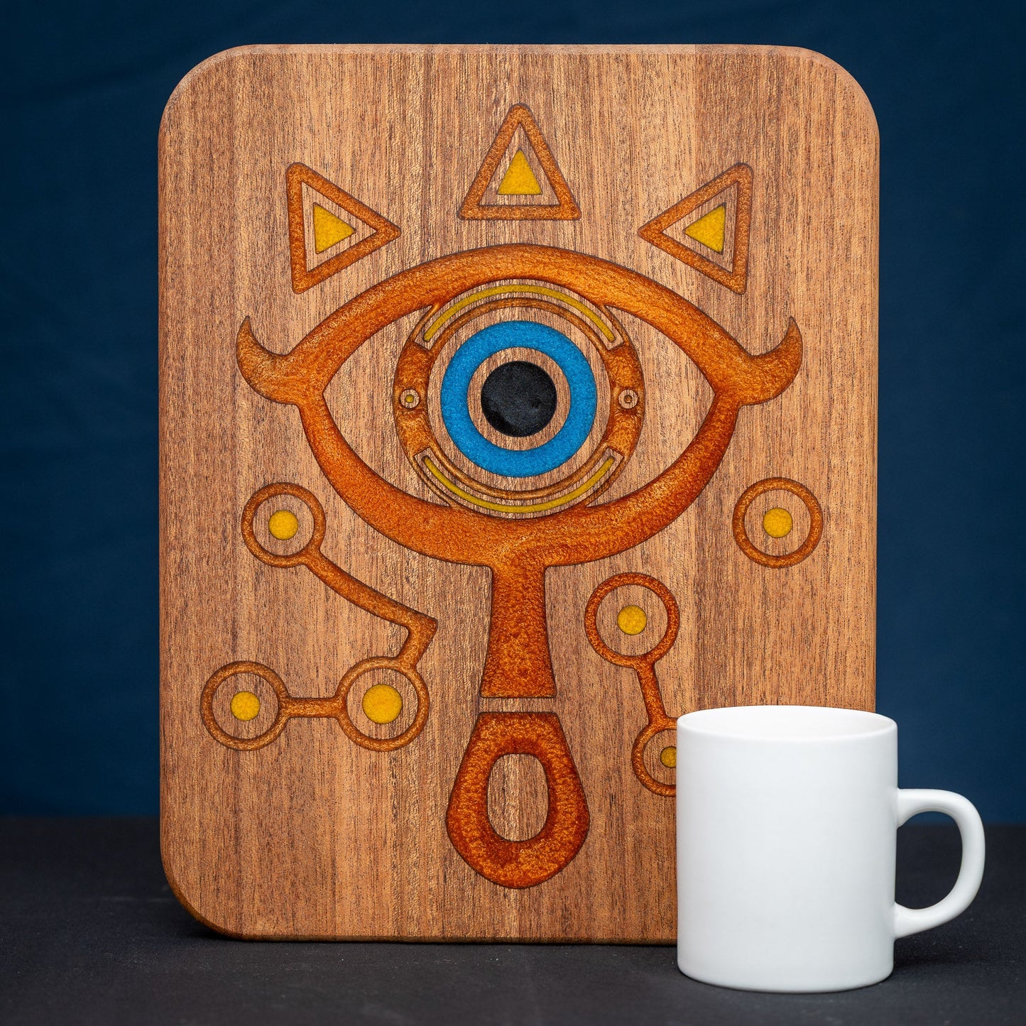 A handmade African Mahogany wooden cutting board featuring the Sheikah eye from the Legend of Zelda video games in resin inlay.