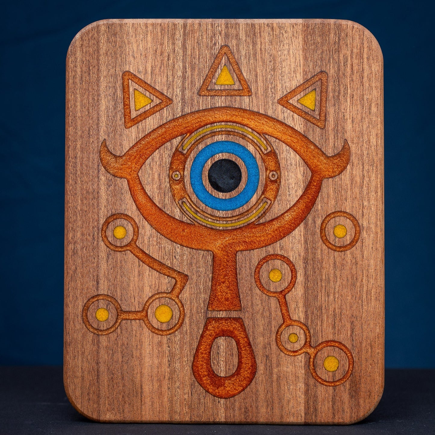 A handmade African Mahogany wooden cutting board featuring the Sheikah eye from the Legend of Zelda video games in resin inlay.