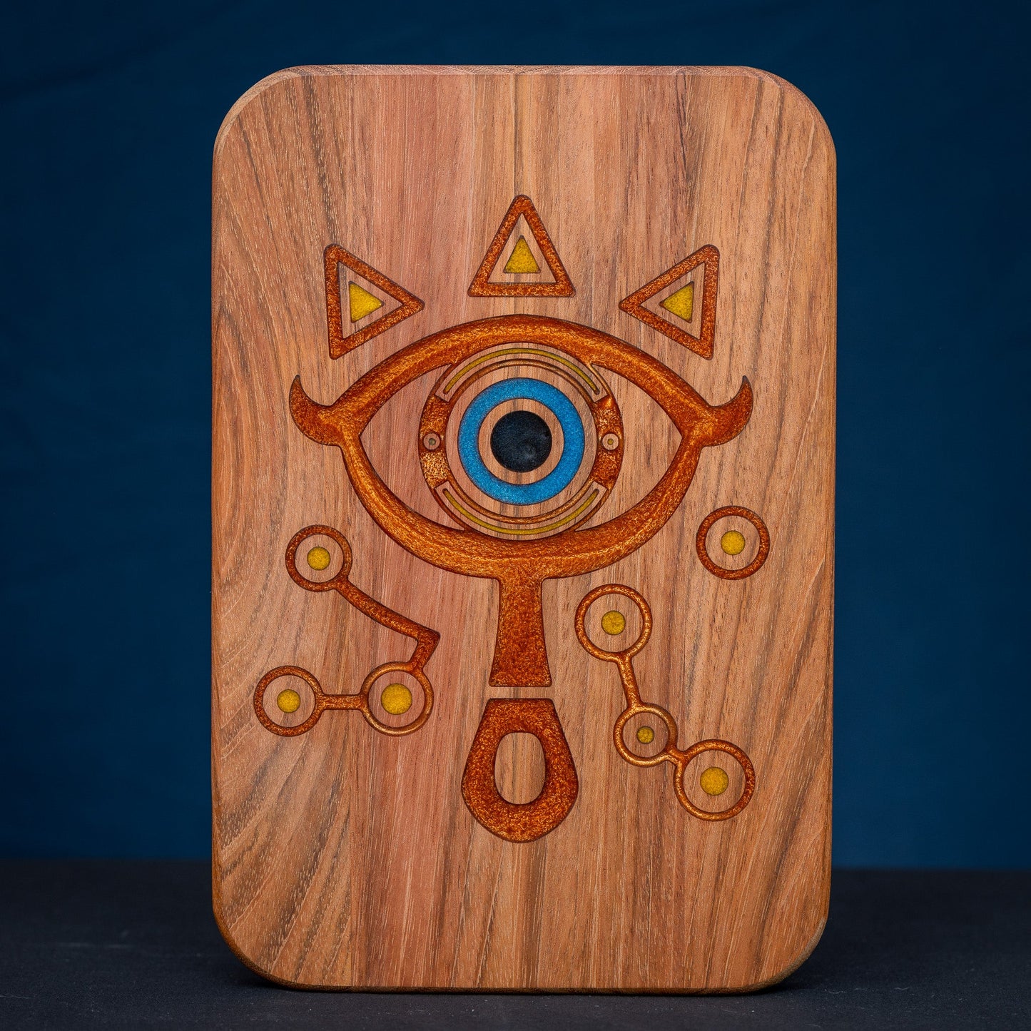 A handmade Jatoba wooden cutting board featuring the Sheikah eye from the Legend of Zelda video games in resin inlay.