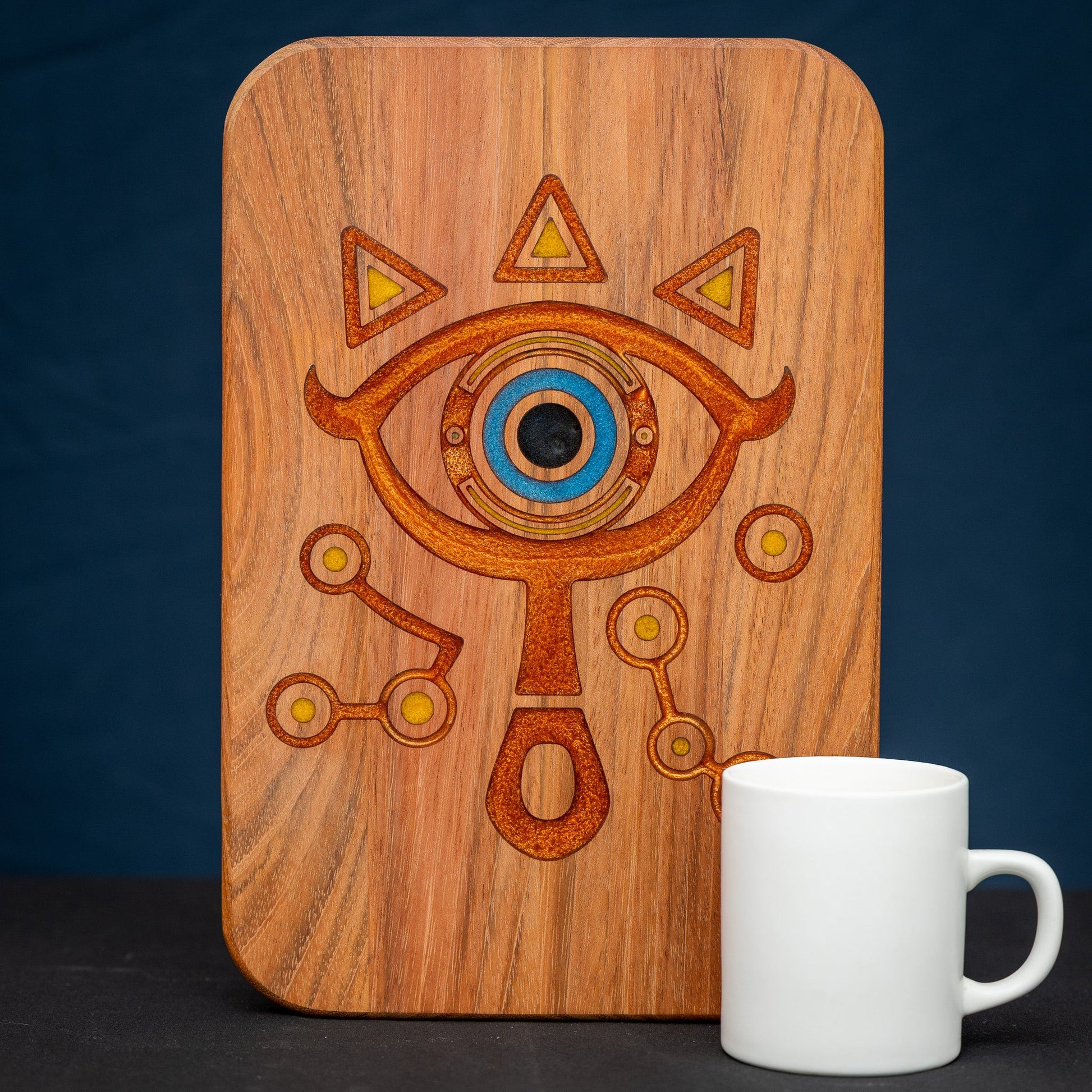 A handmade Jatoba wooden cutting board featuring the Sheikah eye from the Legend of Zelda video games in resin inlay.