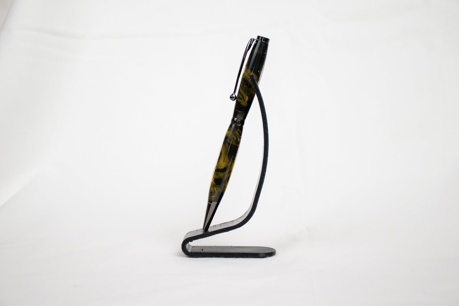 Handmade resin ballpoint twist pen with gold swirls around a black core in gunmetal plating