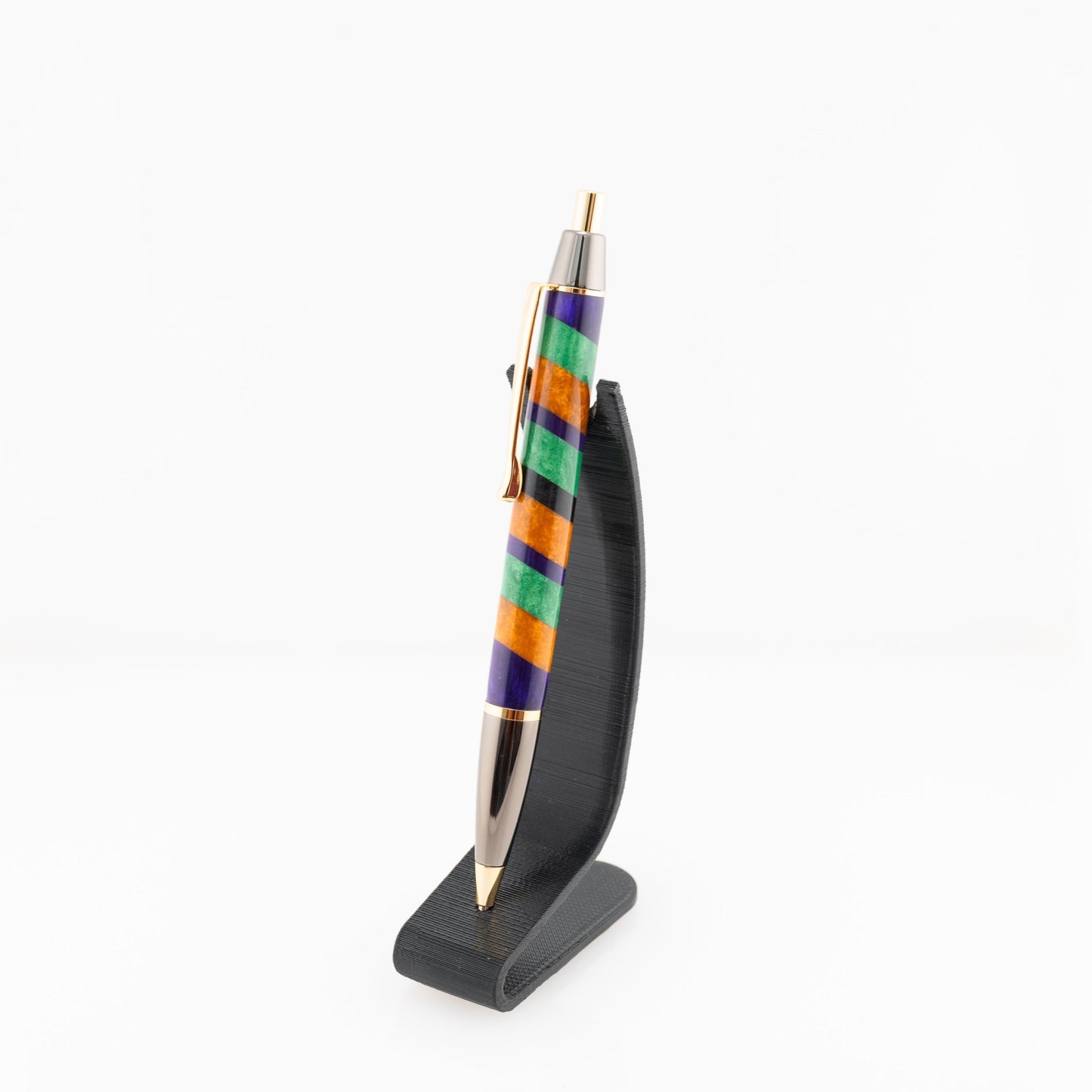 Orange, purple, and green handmade striped resin ballpoint click pen with gold and gunmetal plating on a black stand.