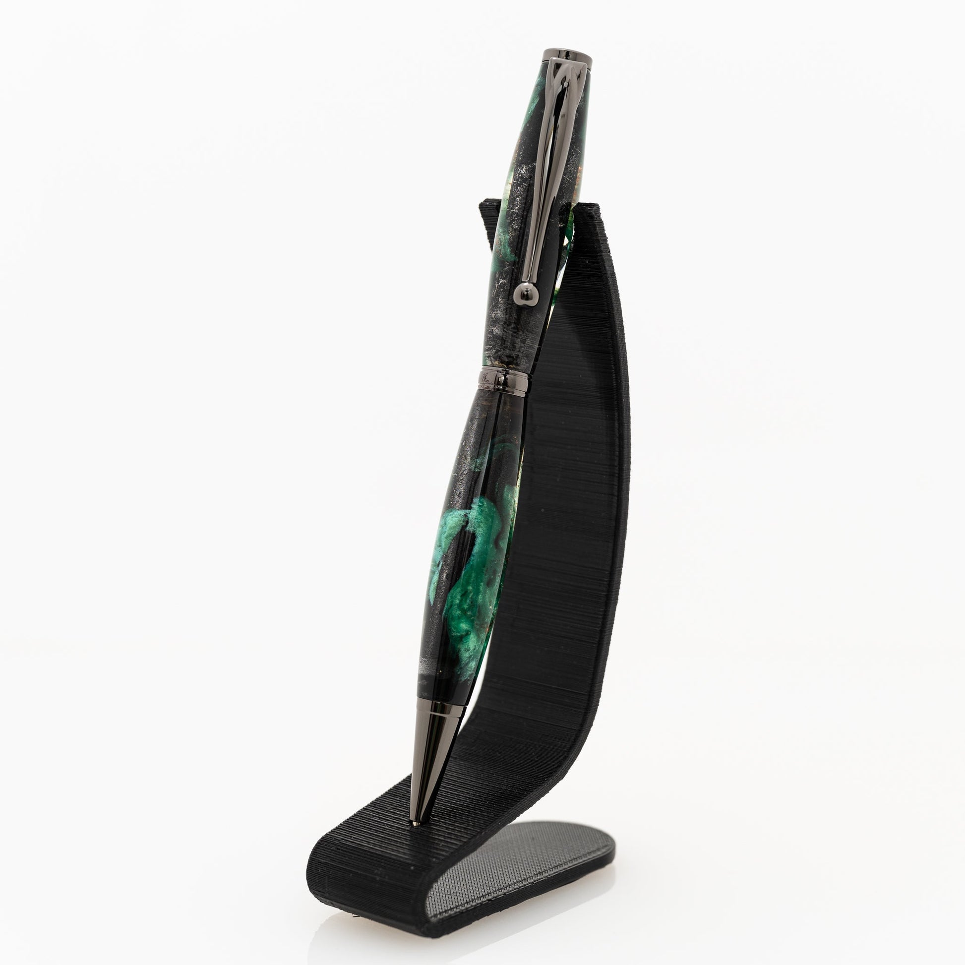 handmade green and black resin ballpoint twist pen on a black stand