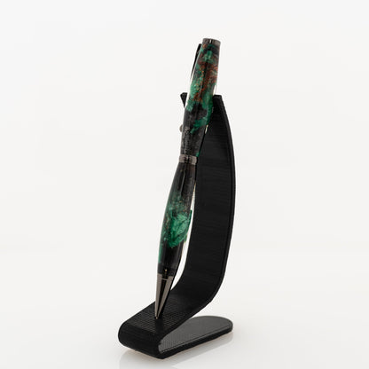 handmade green and black resin ballpoint twist pen on a black stand