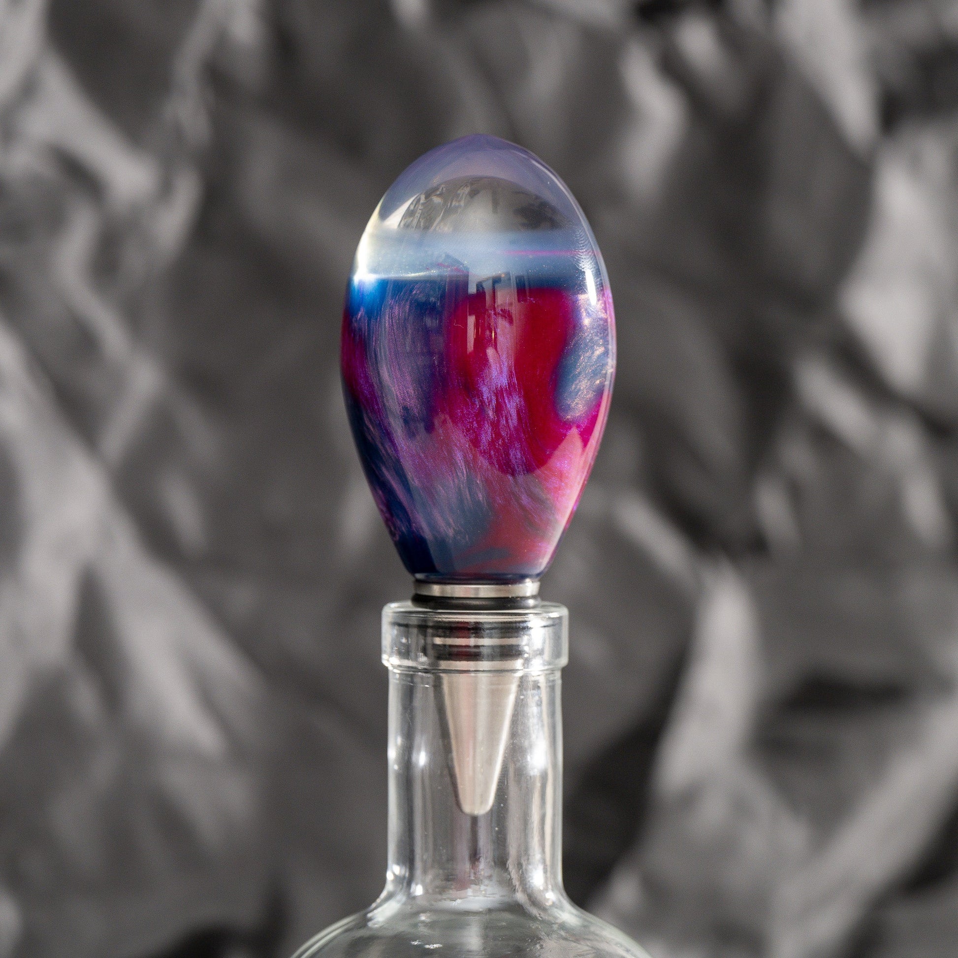 Handmade purple and red resin bottle stopper with a clear domed top, stainless steel dropper, and silicon gaskets