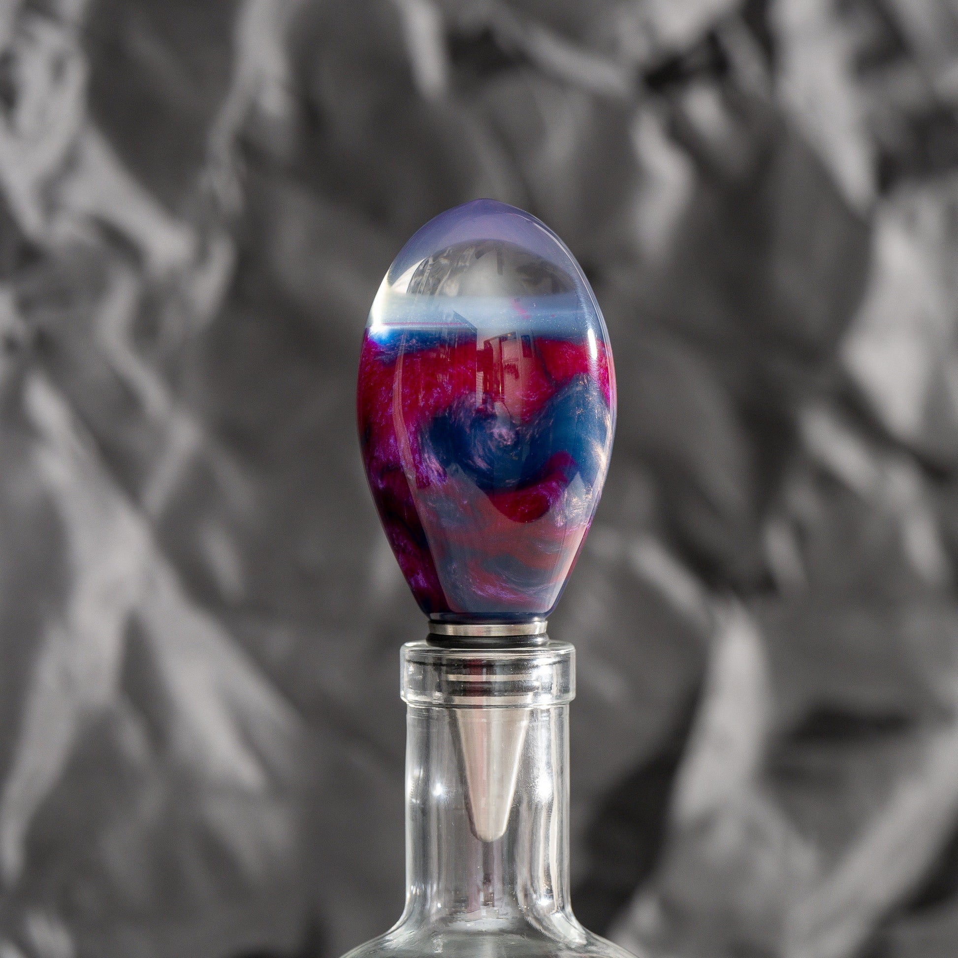 Handmade purple and red resin bottle stopper with a clear domed top, stainless steel dropper, and silicon gaskets