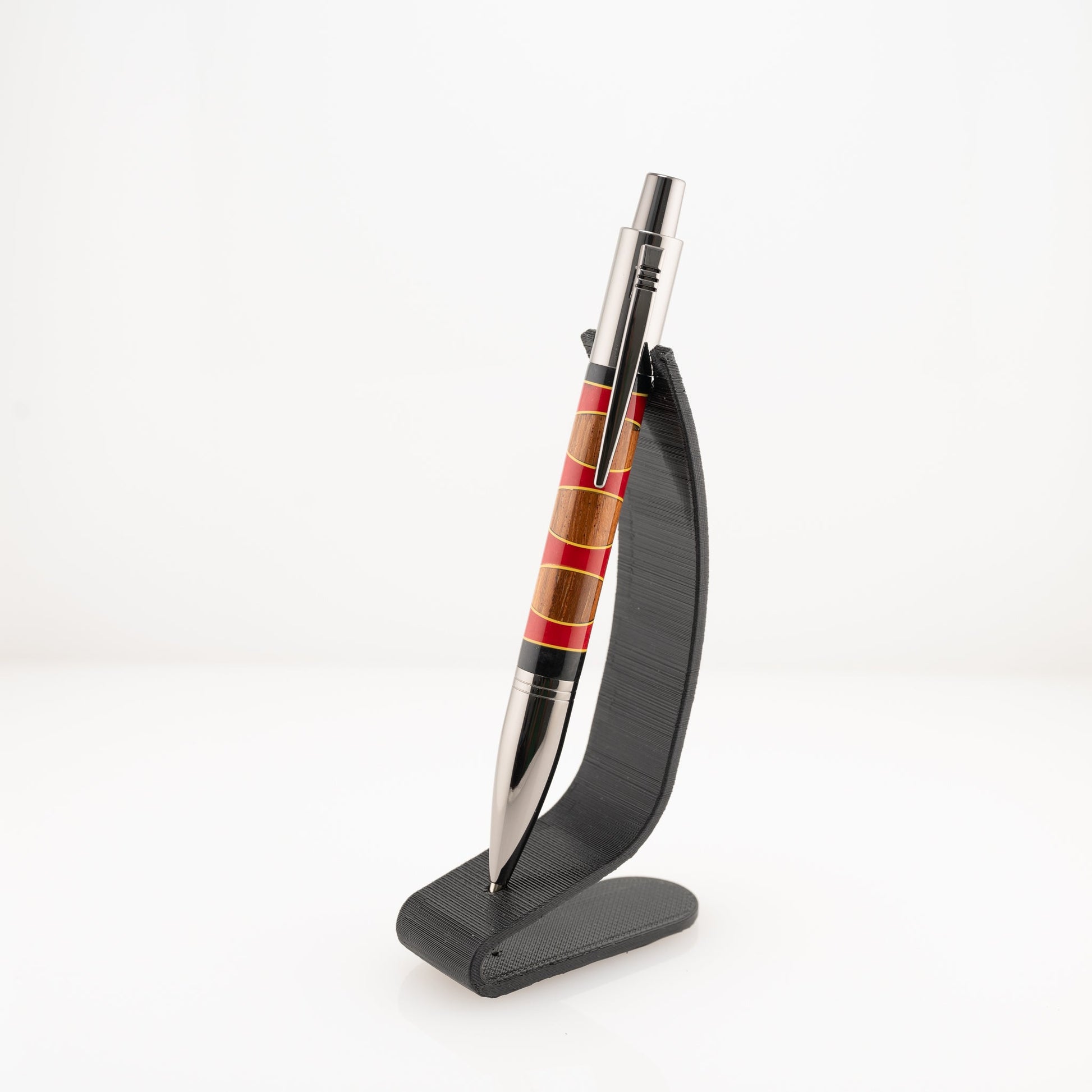 Handmade red and black resin and Canarywood segmented ballpoint click pen on a black stand.