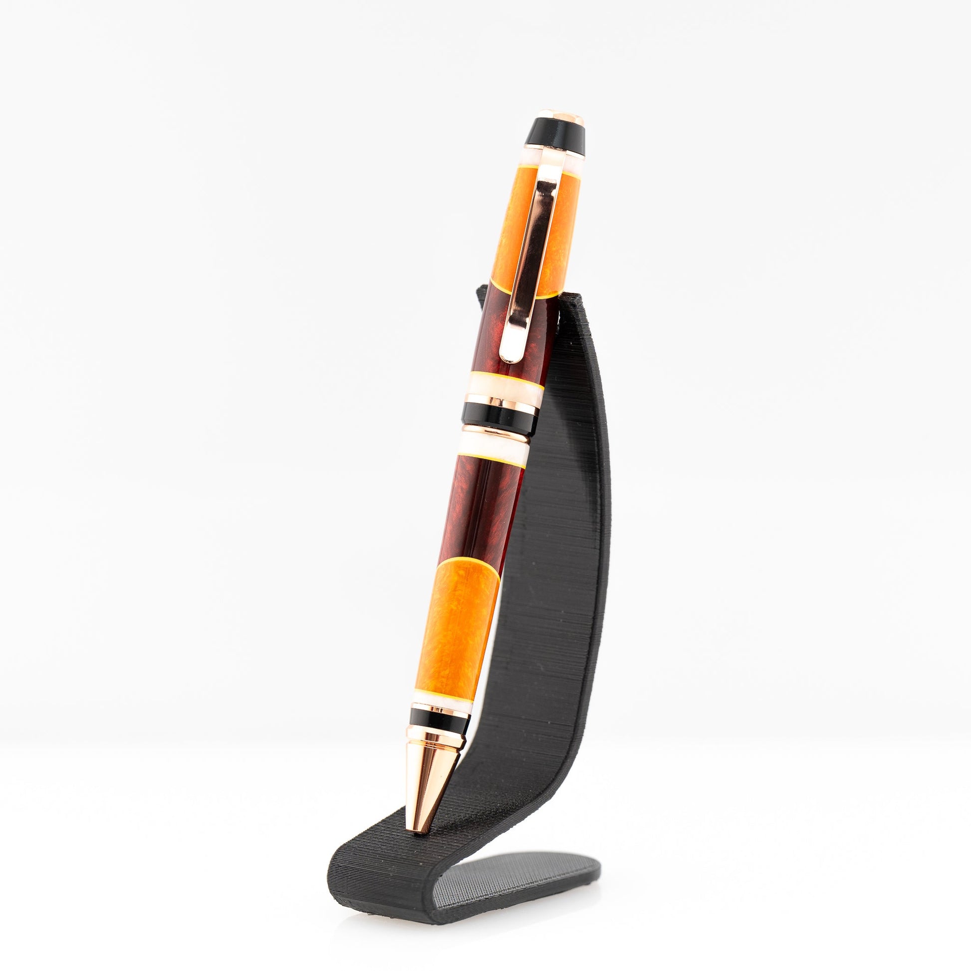 A handmade red, orange, and yellow resin cigar twist ballpoint pen with bright copper plating.