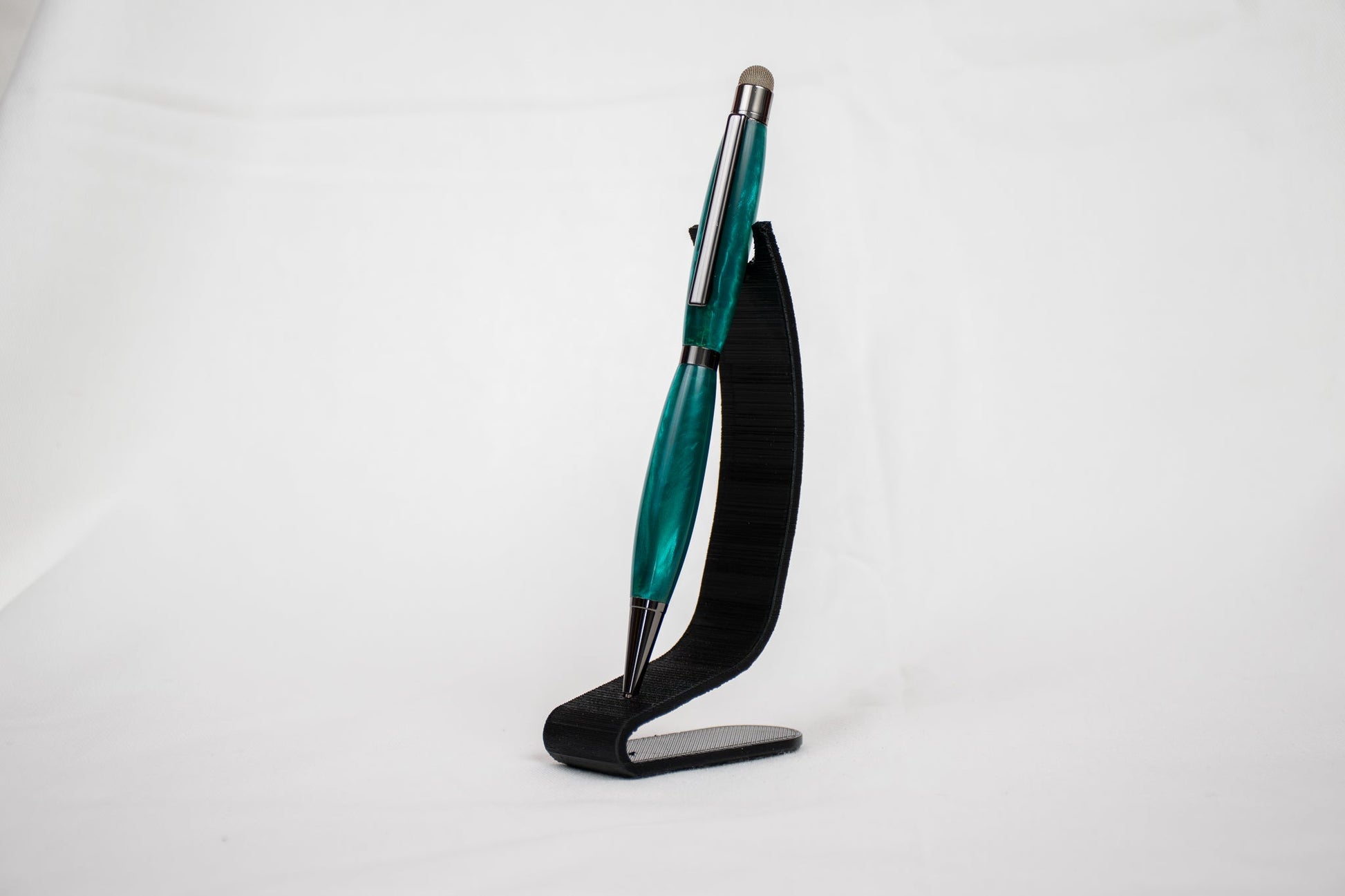 handmade green resin ballpoint twist pen with stylus tip on a black stand