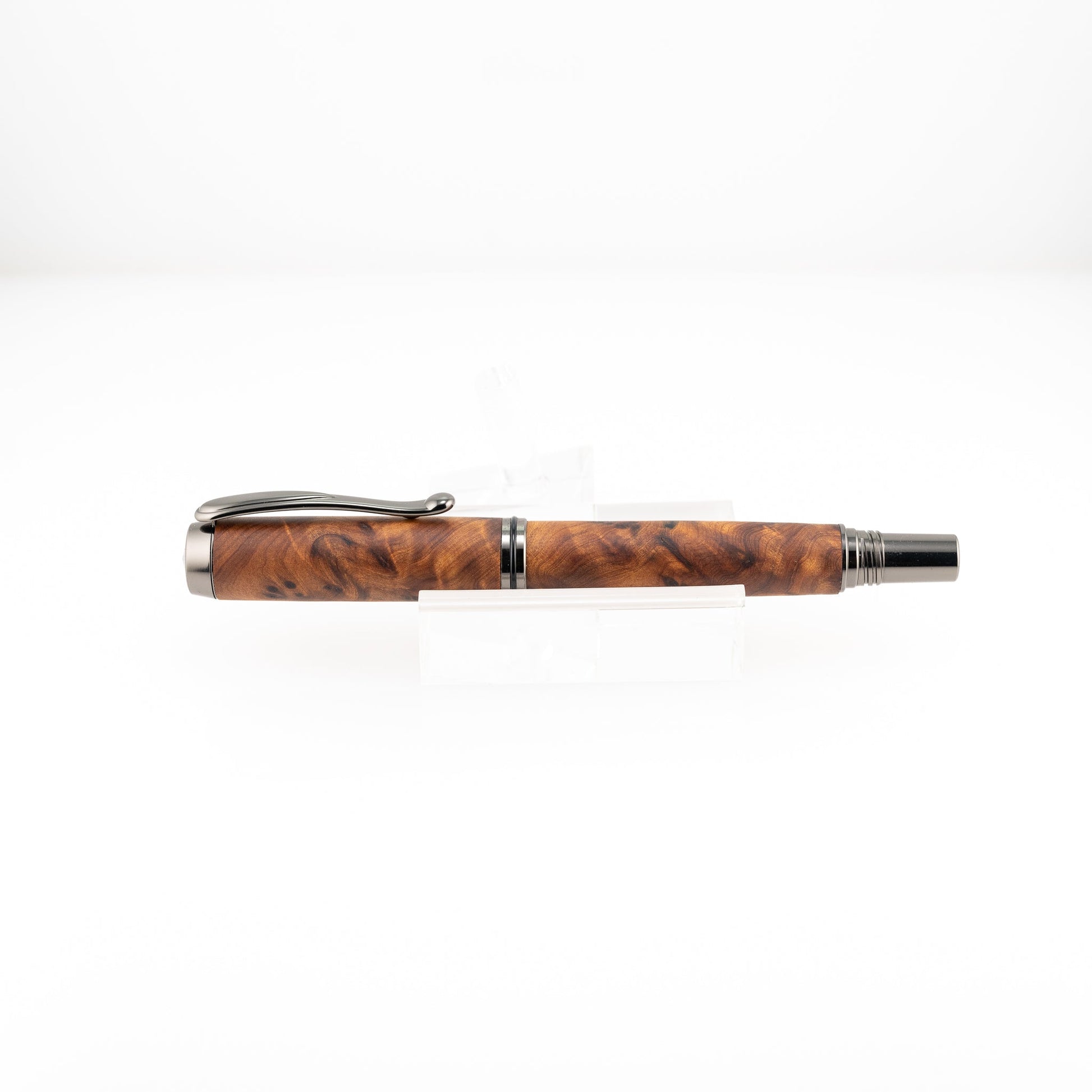 a handmade australian mallee burl rollerball pen with black titanium on a clear stand