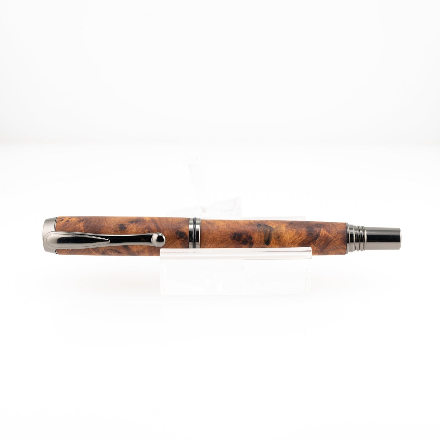 a handmade australian mallee burl rollerball pen with black titanium on a clear stand