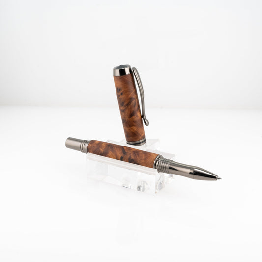 a handmade australian mallee burl rollerball pen with black titanium on a clear stand