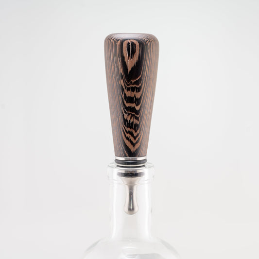 A hanmade Wenge wood bottle stopper rests in a clear bottle. The dropper is stainless steel with three black silicon gaskets.