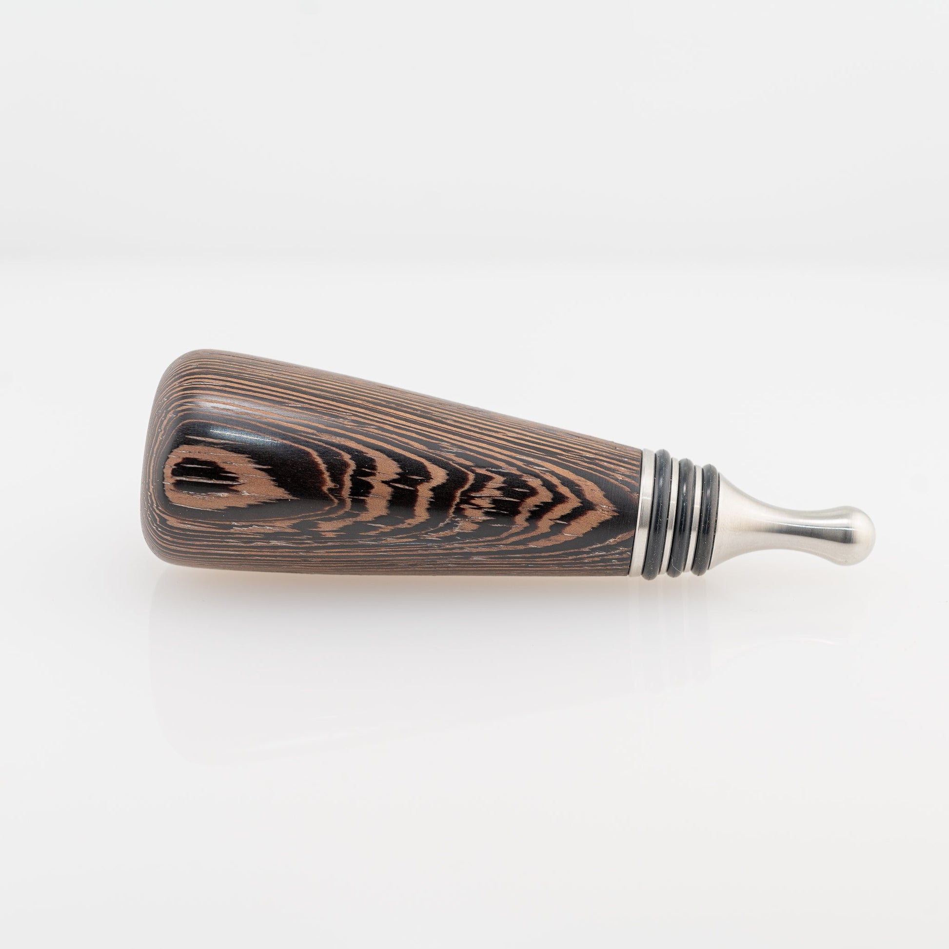 A hanmade Wenge wood bottle stopper rests on its side. The dropper is stainless steel with three black silicon gaskets.